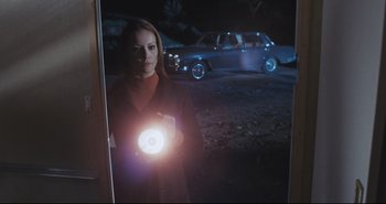 Movie still from “A Bay of Blood” (1971), directed by Mario Bava – A woman holding a flashlight in front of a car; Medium shot, Low angle