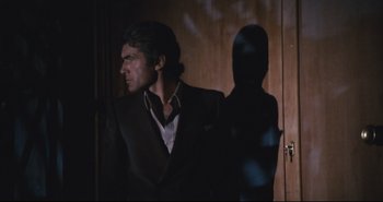 Movie still from “A Bay of Blood” (1971), directed by Mario Bava – A man standing in a dark room next to a wooden wall; Medium shot, Low angle