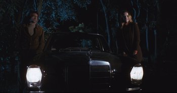 Movie still from “A Bay of Blood” (1971), directed by Mario Bava – A woman standing in front of a car at night; Wide shot, Low angle