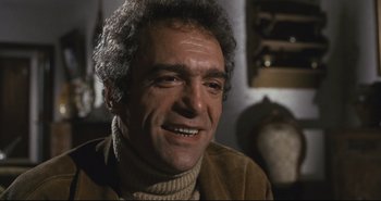 Movie still from “A Bay of Blood” (1971), directed by Mario Bava – A person sitting in a room; Close Up shot, Low angle