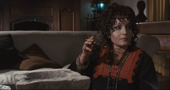 Movie still from “A Bay of Blood” (1971), directed by Mario Bava – A woman sitting on a couch holding up a cell phone; Medium shot, High angle