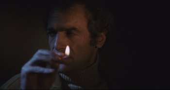 Movie still from “A Bay of Blood” (1971), directed by Mario Bava – A man lighting a cigarette in a dark room; Close Up shot, High angle