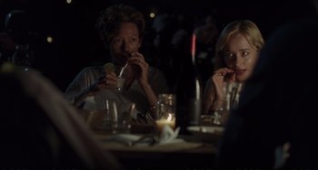 Movie still from “A Bigger Splash” (2015), directed by Luca Guadagnino – Two people sitting at a table eating food; Medium shot, Over the shoulder angle