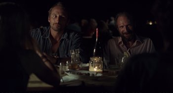 Movie still from “A Bigger Splash” (2015), directed by Luca Guadagnino – A couple of men sitting at a dinner table; Medium shot, Over the shoulder angle
