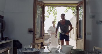 Movie still from “A Bigger Splash” (2015), directed by Luca Guadagnino – A man and a woman standing in front of an open door; Medium shot, Low angle