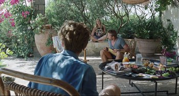 Movie still from “A Bigger Splash” (2015), directed by Luca Guadagnino – A group of people sitting around a table; Wide shot, Over the shoulder angle