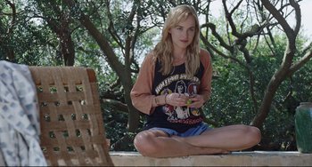 Movie still from “A Bigger Splash” (2015), directed by Luca Guadagnino – A woman sitting on the ground holding a cell phone; Medium shot, High angle