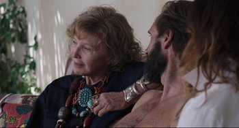 Movie still from “A Bigger Splash” (2015), directed by Luca Guadagnino – An older woman sitting next to a bearded man; Close Up shot, Over the shoulder angle