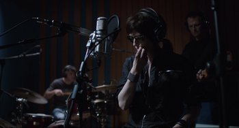 Movie still from “A Bigger Splash” (2015), directed by Luca Guadagnino – A man in a recording studio with a microphone; Close Up shot, Over the shoulder angle