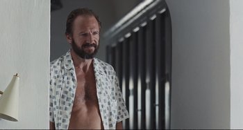 Movie still from “A Bigger Splash” (2015), directed by Luca Guadagnino – A man with a beard and mustache wearing a white shirt; Medium shot, Low angle