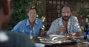 Movie still from “A Bigger Splash” (2015), directed by Luca Guadagnino – A man and a woman sitting at a table with food; Medium shot, Over the shoulder angle