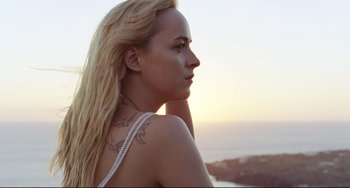 Movie still from “A Bigger Splash” (2015), directed by Luca Guadagnino – A woman with long blonde hair and a tattoo on her shoulder; Close Up shot, Low angle