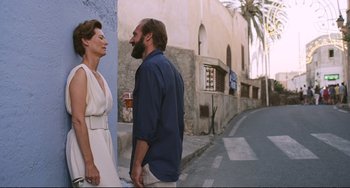 Movie still from “A Bigger Splash” (2015), directed by Luca Guadagnino – A man and a woman standing next to each other on a street; Medium shot, Over the shoulder angle