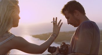 Movie still from “A Bigger Splash” (2015), directed by Luca Guadagnino – A man and a woman smoke a cigarette while holding a camera; Close Up shot, Over the shoulder angle
