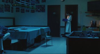 Movie still from “A Bigger Splash” (2015), directed by Luca Guadagnino – A person standing in front of a dining room table; Wide shot, Over the shoulder angle