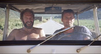 Movie still from “A Bigger Splash” (2015), directed by Luca Guadagnino – Two shirtless men in a car looking out the window; Medium shot, Low angle