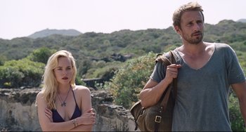 Movie still from “A Bigger Splash” (2015), directed by Luca Guadagnino – A man and a woman standing next to each other on top of a hill; Medium shot, Over the shoulder angle