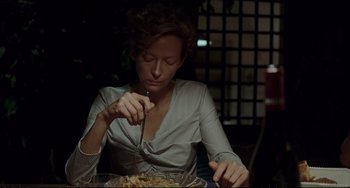 Movie still from “A Bigger Splash” (2015), directed by Luca Guadagnino – A woman sitting in front of a bowl of food; Medium shot, High angle