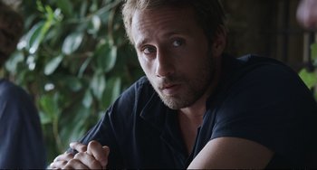 Movie still from “A Bigger Splash” (2015), directed by Luca Guadagnino – A person with a beard; Close Up shot, Over the shoulder angle