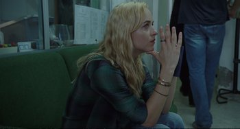 Movie still from “A Bigger Splash” (2015), directed by Luca Guadagnino – A woman sitting on a green chair clapping her hands; Close Up shot, Over the shoulder angle