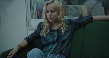 Movie still from “A Bigger Splash” (2015), directed by Luca Guadagnino – A woman sitting on a couch in a room; Medium shot, High angle