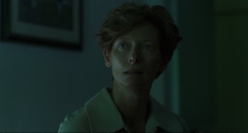 Movie still from “A Bigger Splash” (2015), directed by Luca Guadagnino – A woman with short brown hair is looking at the camera; Close Up shot, Over the shoulder angle