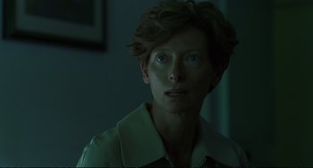 Movie still from “A Bigger Splash” (2015), directed by Luca Guadagnino – A woman with short brown hair is looking at the camera; Close Up shot, Over the shoulder angle