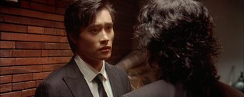 A man wearing a suit and tie talking to another man