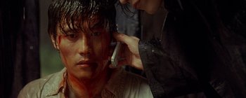 A man with blood on his face is on a cell phone