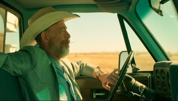 An older man sitting in the driver's seat of a car