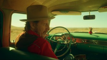 A man wearing a hat sitting in the driver's seat of a car