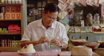 Movie still from “A Brighter Summer Day” (1991), directed by Edward Yang – A man sitting at a table looking at a piece of cake; Medium shot, Low angle