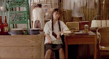 Movie still from “A Brighter Summer Day” (1991), directed by Edward Yang – A girl sitting at a table with a book in her lap; Medium shot, High angle
