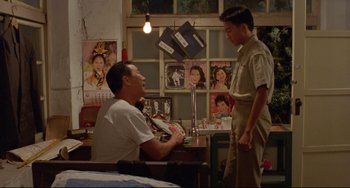 Movie still from “A Brighter Summer Day” (1991), directed by Edward Yang – Two men talking in a room with posters on the wall; Medium shot, High angle