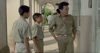 Movie still from “A Brighter Summer Day” (1991), directed by Edward Yang – A group of young men standing next to each other on a sidewalk; Medium shot, Over the shoulder angle