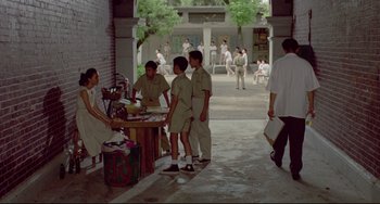 Movie still from “A Brighter Summer Day” (1991), directed by Edward Yang – A group of young men standing around a table; Wide shot, High angle