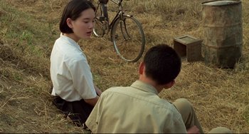 Movie still from “A Brighter Summer Day” (1991), directed by Edward Yang – A girl and a boy sitting in a field with a bicycle in the background; Medium shot, High angle