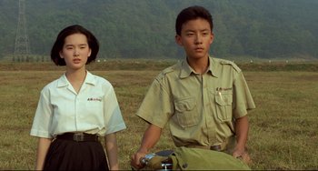Movie still from “A Brighter Summer Day” (1991), directed by Edward Yang – A man and a woman standing next to each other in an open field; Medium shot, High angle