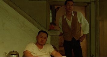 Movie still from “A Brighter Summer Day” (1991), directed by Edward Yang – Two men in white shirts and brown vests standing next to each other in a room; Medium shot, High angle