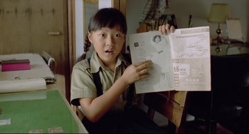 Movie still from “A Brighter Summer Day” (1991), directed by Edward Yang – A young girl holding up a piece of paper in front of her face; Close Up shot, High angle