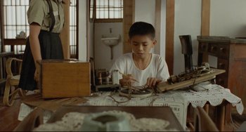 Movie still from “A Brighter Summer Day” (1991), directed by Edward Yang – A young boy is sitting at a table and painting; Medium shot, High angle