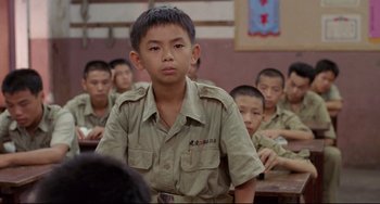 Movie still from “A Brighter Summer Day” (1991), directed by Edward Yang – A young boy in a military uniform in front of a group of other young boys; Medium shot, Over the shoulder angle
