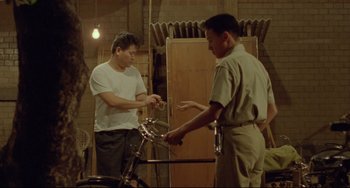Movie still from “A Brighter Summer Day” (1991), directed by Edward Yang – Two men standing next to each other in front of a bicycle; Wide shot, High angle
