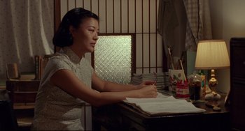 Movie still from “A Brighter Summer Day” (1991), directed by Edward Yang – A woman sitting at a desk writing on a piece of paper; Medium shot, High angle