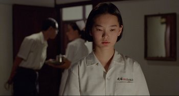 Movie still from “A Brighter Summer Day” (1991), directed by Edward Yang – A woman in a white shirt is standing in front of a group of people; Close Up shot, Over the shoulder angle