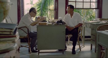 Movie still from “A Brighter Summer Day” (1991), directed by Edward Yang – Two men are sitting at a table and one of the men is eating; Medium shot, Low angle