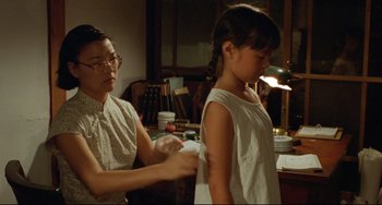 Movie still from “A Brighter Summer Day” (1991), directed by Edward Yang – A young girl getting help from an older woman; Medium shot, Over the shoulder angle