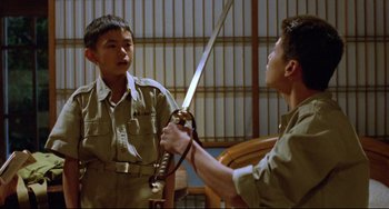 Movie still from “A Brighter Summer Day” (1991), directed by Edward Yang – Two young men are holding swords in a room; Medium shot, Over the shoulder angle