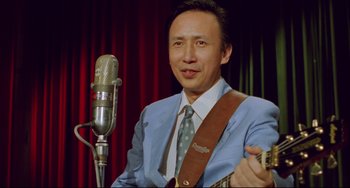 Movie still from “A Brighter Summer Day” (1991), directed by Edward Yang – A man in a suit and tie playing a guitar; Close Up shot, Low angle
