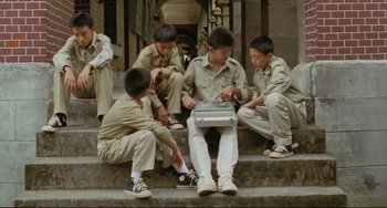 Movie still from “A Brighter Summer Day” (1991), directed by Edward Yang – A group of young men sitting on some steps; Wide shot, High angle